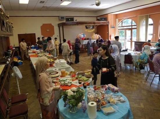 A community hall arranged with food tables for a MAUK gathering
